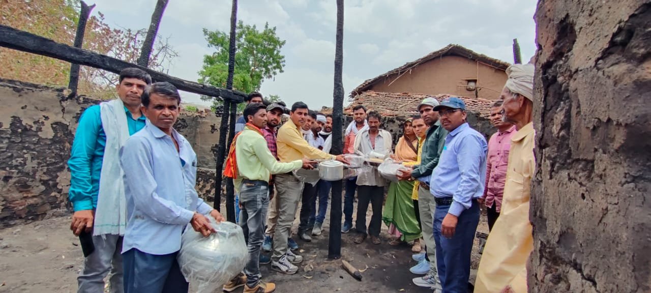 आदिवासी समाज द्वारा घर जलकर हुए ख़ाक परिवार को सौंपे गये घर में उपयोगी बर्तन एवं खाद्य सामग्री गेहूं | New India Times